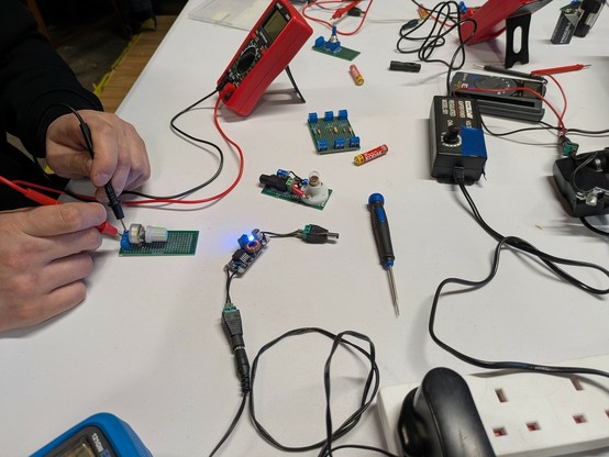 A table full of tools, A pair of hands hold a muit meter