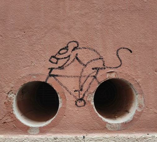 Graffiti of a mouse in a gas mask riding a bicycle