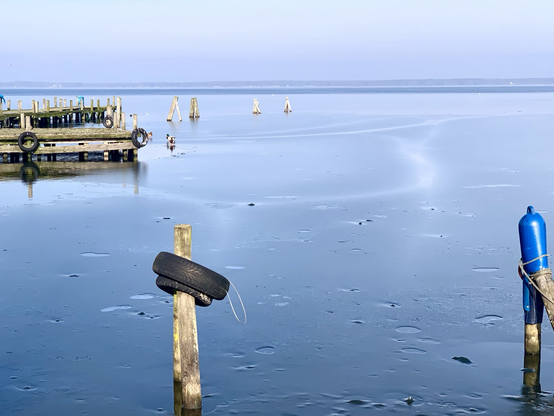 Das noch gefrorene Steinhuder Meer im Februar. Leere Bootsanleger, Pfähle und Bojen bei klarem Wetter morgens.