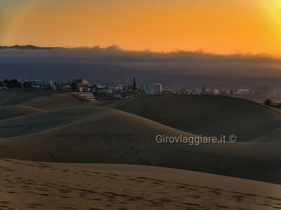 Le dune di Maspalomas con la città sullo sfondo. Colori caldi dell'alba