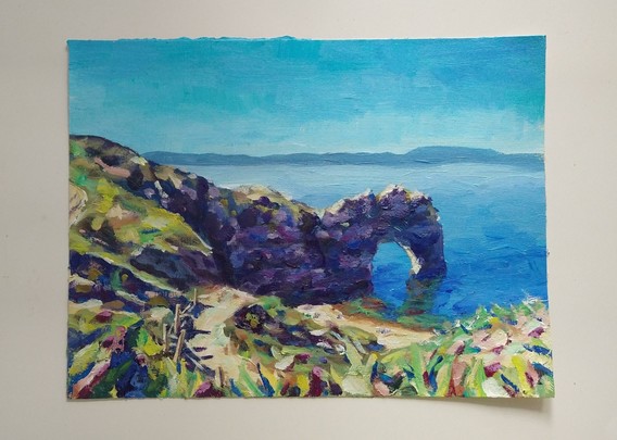 Acrylic painting of a limestone arch near a coast. There is a path in the foreground leading up to it. It's a painting on a piece of paper lying on a white table.