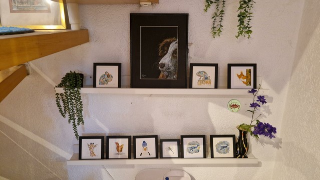 Auf zwei Borden aufgereiht sind 11 handgemalte Bilder, eins davon ein unverkäufliches Portrait meiner Hundedame auf den anderen zweimal Chamäleon  zweimal Wal, einmal Möwe mit Mütze, einmal Giraffe, einmal Eichhörnchen,einmal Huhn und einmal Libelle