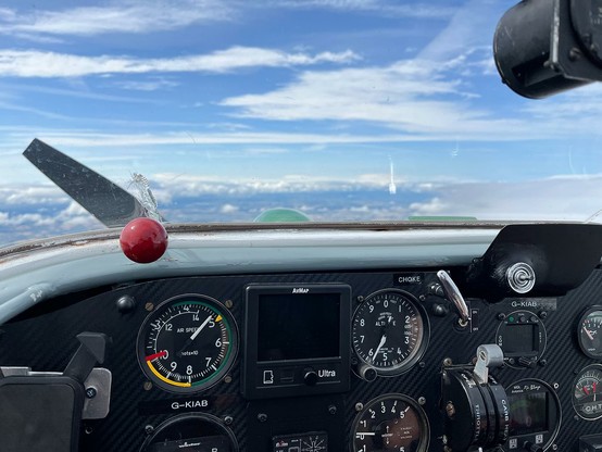 cockpit shot showing instrument panel and clouds on the far horizon