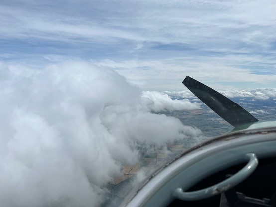 cockpit shot flying alongside a tall bank of fluffy white cloud