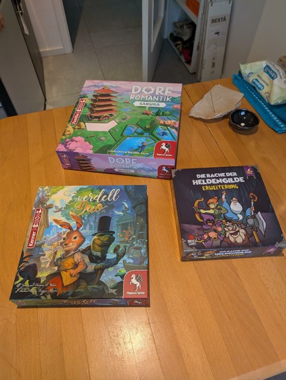 Drei Brettspiele im Karton: Dorfromantik Sakura, Helden müssen draußen bleiben, Everdell Duett