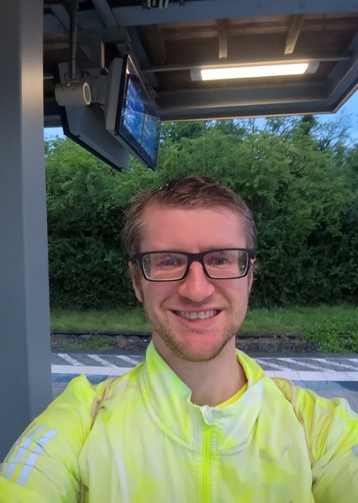 Selfie of myself. I wear glasses and a bright yellow sports jacket.
The picture was taken at a train station.