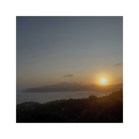 sundown over the hilly coastline of elba, tuscany, italy. the sun looks like a glooming red ball, the hills are already pitch black. far in the distance the mountains are colored in a slightly reddish tone