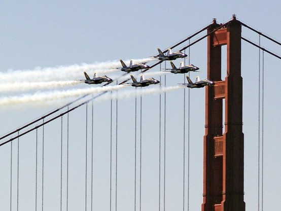 Blue Angels And The Bridge

This is an image of the US Navy's precision flying team, The Blue Angels. They are flying northeasterly as the pass the south tower of the Golden Gate Bridge. 
This route takes them over the San Francisco Bay and into San Francisco.
In this image you can see all 6 jets flying in tight formation as they pass the south tower of the bridge. The cables stretch out and hang down towards the deck of the bridge. All 6 jets are trailing smoke out of the rear of the jets as they make their entrance.
