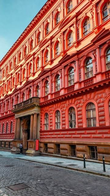 Shot from across the street of an impossibly red building with sculptural recesses showing an interplay of light and shadow.