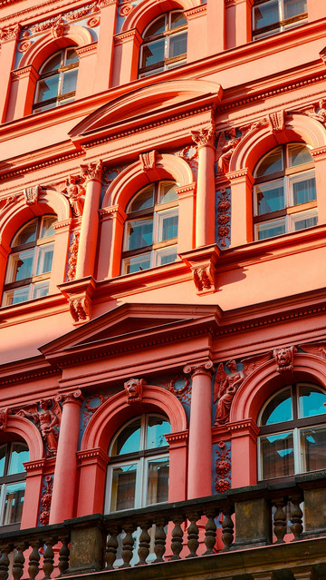 Second detail shot of an impossibly red building with sculptural recesses showing an interplay of light and shadow.