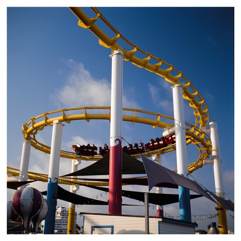 A rollercoaster train making a loop above a tent in the Santa Monica Pier.