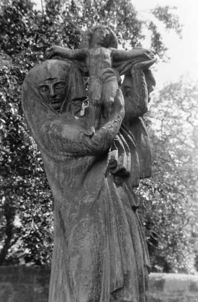 A black and white photograph of a statue of a mother holding a child aloft