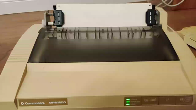 A Commodore MPS 1200 dot matrix printer (loudly) prints a test pattern on tractor feed paper.