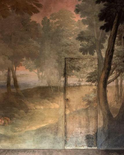 A wall and a door, fully covered in a mural with a forest motif