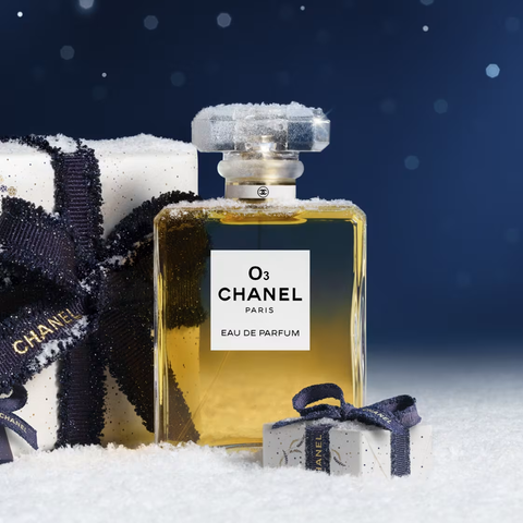Bottle of Chanel Number 5 perfume with a gift box to your left, slightly dusted in snow. The N O 5 on the label has been replaced with O 3.
