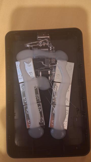 An opened up counterfeit drive. It has steel weights hot-glued in to add mass, and a tiny circuit board with an SD card attached.