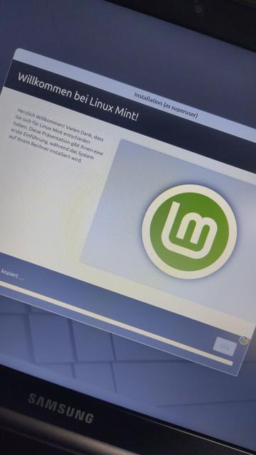 Das Bild zeigt einen Laptop Bildschirm mit dem Linux Mont Logo in grün während es auf dem Rechner installiert wird.