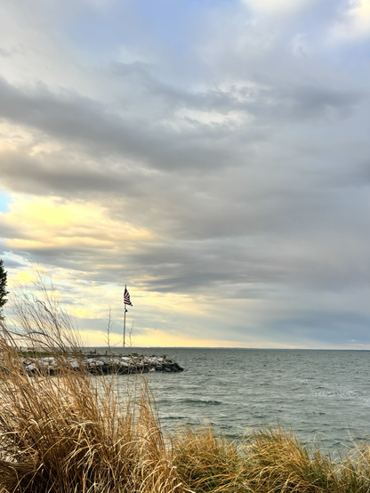 Looking out over the Chesapeake Bay in the morning. A flag is perched off of a rock jetty.