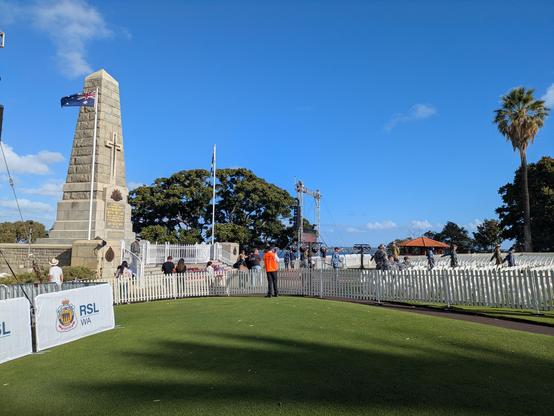 A photograph of the war memorial at the top of Kings Park. There are temporary white picket fences around the memorial, and the path leading towards it.

There are a number of people in camouflage uniforms standing around, and four matching away at the right of the photo.