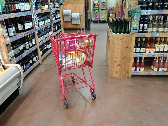 Shopping cart parked in the middle of the aisle. The shopper left it at an angle, so it takes up extra room and there's no way to squeeze by either side.