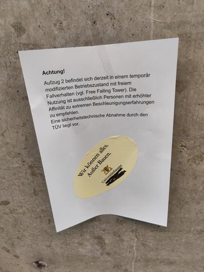 Achtung!
Aufzug 2 befindet sich derzeit in einem temporär mofifiziertem Betriebszustand mit freiem Fallverhalten (vgl. Free Falling Tower). Die Nutzung ist ausschließlich Personen mit riner Affinität zu extremen Beschleunigungen zu empfehlen. 
Eine sicherheitstechnische Abnahme durch den TÜV liegt vor.

Darunter ein Sticker mit der Aufschrift: Wir können alles.
Außer Bauen.
Universitätsbauamt