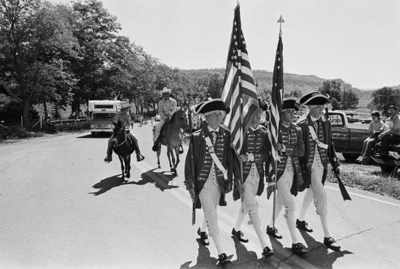 A black and white photo of the flag bearers in a revolutionary reinactment.