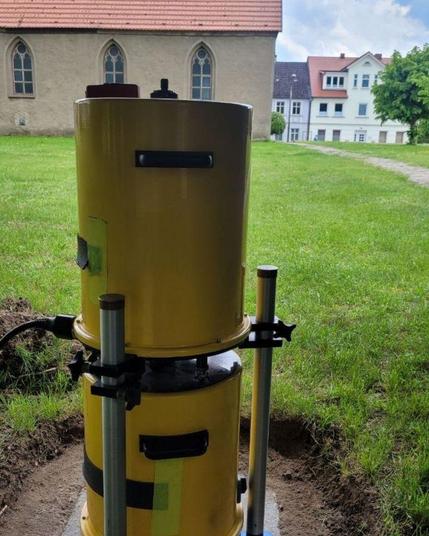 Im Vordergund ein Absolutgravimeter. Im Hintergrund eine gotische Kirche