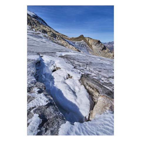 Photo d'un paysage de montagne.
Au premier plan on voit un trou rempli de neige, entouré de la glace grise d'un glacier en fin d'été. En arrière plan on distingue l'arrête d'une montagne contre laquelle vient mourir le glacier.
-
Photo of a mountain landscape.
In the foreground is a snow-filled hollow, surrounded by the gray ice of a glacier in late summer. In the background, the ridge of a mountain is visible, where the glacier comes to an end.