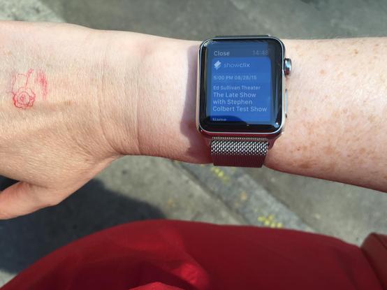 A woman’s hand with an Apple Watch. The screen shows a mobile ticket with text 
“5:00 PM 08/28/15
Ed Sullivan Theater
The Late Show with Stephen
Colbert Test Show”
