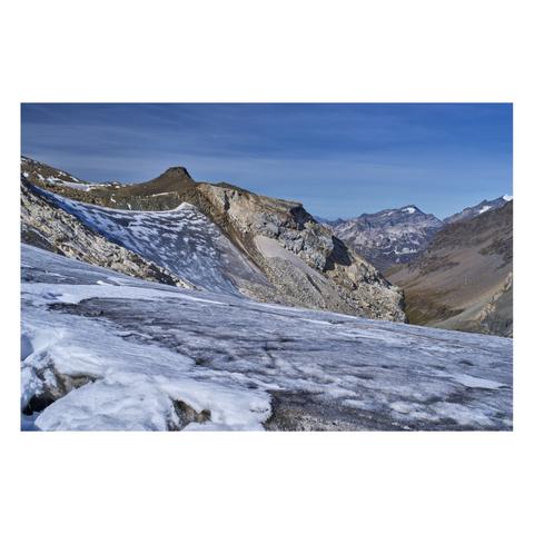Photo d'un paysage de montagne.
Le premier plan est occupé par de la neige allant du blanc au gris sale de la vieille glace qui ressort à la surface du glacier à la faveur du réchauffement. Les montagnes à l'arrière-plan sont minérales, sur la gauche on remarque une pente de glace assez raide, la glace noirâtre est curieusement mouchetée de blanc.
-
Photo of a mountain landscape.
The foreground is covered in snow ranging from white to the dirty gray of old ice that has risen to the surface of the glacier as a result of warming. The mountains in the background are rugged; on the left, a fairly steep ice slope is visible, its blackish ice curiously speckled with white.