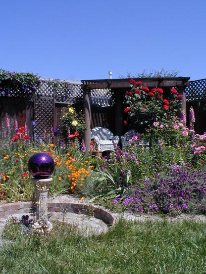 Backyard, cottage garden with a gazing ball in the middle of radiating brick paths.