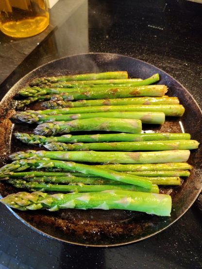 Butter fried fresh green asparagus on a hot metal pan
