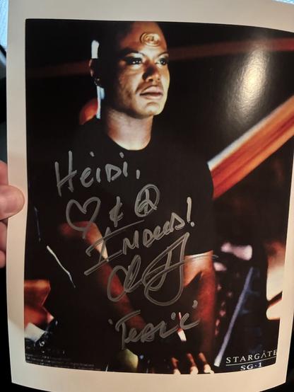 An autographed picture of Teal’c from SG-1 standing on the bridge of a starship.