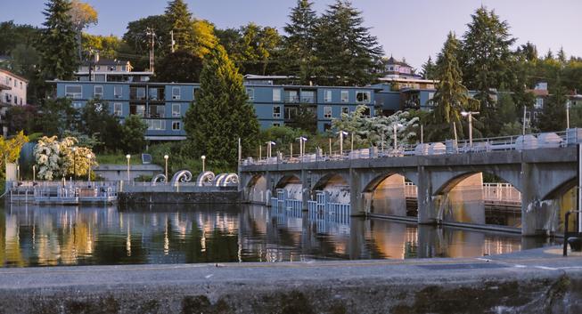 A heavily stylized landscape photo of the Hiram M. Chittenden Locks from the freshwater side with the Salmon Waves sculptures reflecting off the water.
