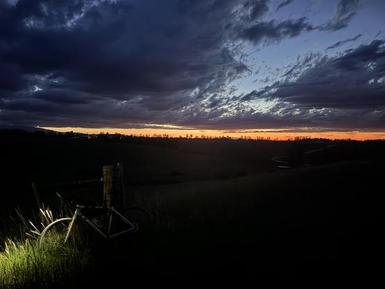 A late sunset sky with high wispy clouds and a gravel bike barely visible in the lower left shadows