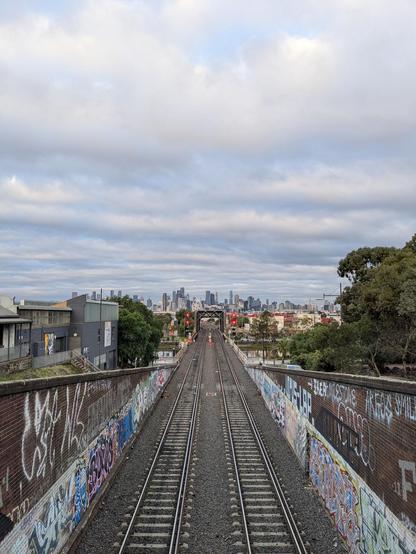 a photograph shot from above the Bunbury St rail tunnel portal looking toward the Melbourne CBD at which the twin rail lines and bridge very nicely line up into the distance ... a classic location for train enthusiasts in Melbourne ...