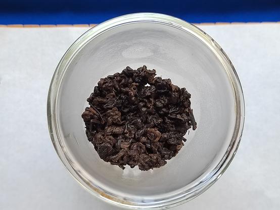 Another closeup view of the tea, this time after a brief wash, provides a detailed look at the initial process of the leaves' unfurling and brewing.  The coloration has spread out to be a bit more evenly distributed, the tight curls have visibly loosened, and the now-damp leaves glisten in the ambient light.

At this point, the famed Dianhong floral bouquet fills the immediate vicinity with an almost incense-like scent – familiar to the fortunate who recognize it as a sign of what's to come.