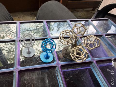 Resin printed dodecahedra next to a casting of a tree with four dodecahedra