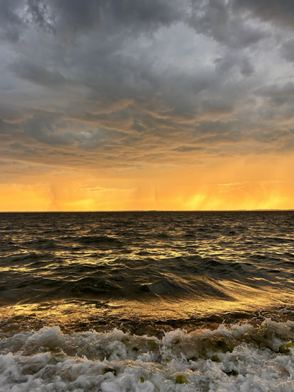 Dramatic clouds over the bay as storms roll through at sunset. The horizon lit up