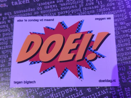 Een foto van een sticker met grote oranje cartoon letters de tekst "DOEI!", voor een rode cartoon knal achtergrond.