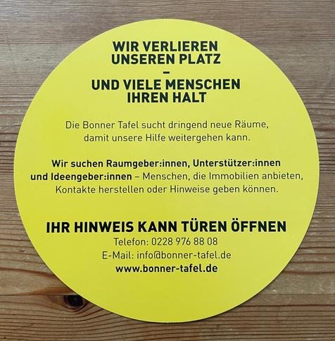 Foto eines runden gelben Flyers mit dem Text: 
WIR VERLIEREN UNSEREN PLATZ UND VIELE MENSCHEN IHREN HALT

Die Bonner Tafel sucht dringend neue Räume, damit unsere Hilfe weitergehen kann.

Wir suchen Raumgeber:innen, Unterstützer:innen und Ideengeber:innen - Menschen, die Immobilien anbieten, Kontakte herstellen oder Hinweise geben können.

IHR HINWEIS KANN TÜREN ÖFFNEN

Telefon: 0228 976 88 08

E-Mail: info@bonner-tafel.de

www.bonner-tafel.de