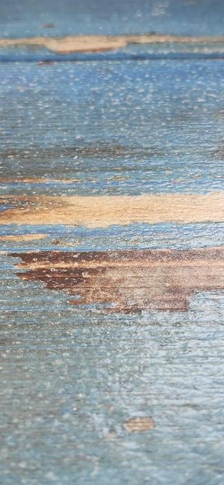 Vertical close-up of a picnic table. Originally painted blue but well-worn with wood showing through.