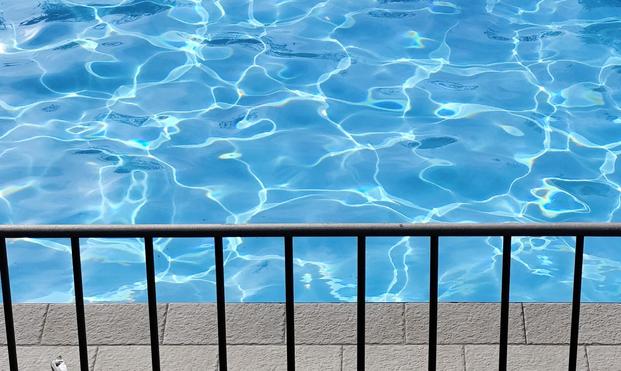 Poolbild mit Reflektionen. davor ein Geländer