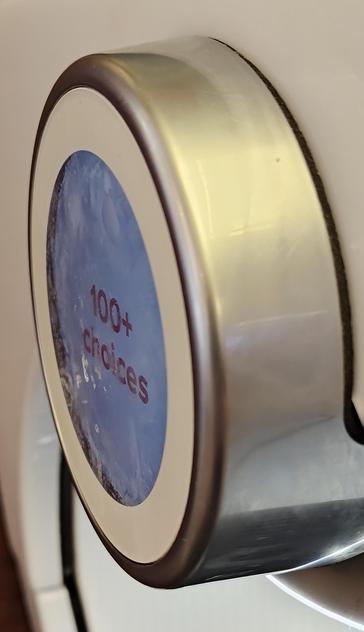 The "pour" button of a coca cola freestyle equinox machine from an extreme angle to show the mess of fingerprints and schmutz smeared all over the surface that you have to solidly press with a actual finger to activate
