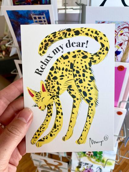 A photo of a postcard I hold in my hand. It shows a yellow, leopard-spotted cat that is stretching, with the words "Relax my dear!" above it.