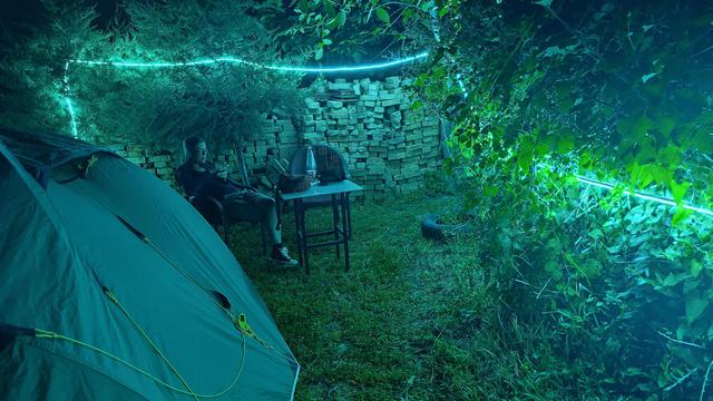 grüner Leuchtschlauch läuft an der Mauer eines Campingplatzes entlang und beleuchtet unser Zelt