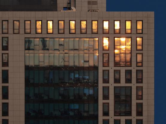 Gray building with multiple glass windows glowing from sunset