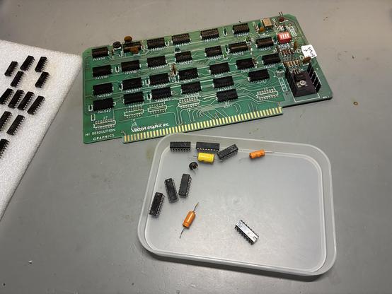 A Vector Graphics High Resolution Graphics board for S-100 computers. All ICs have been removed. Seven of these sit in a tray nearby, with three axial capacitors and an old style flying-saucer transistor.