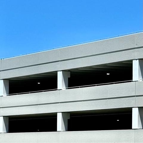 Grey parking garage against a bright blue sky