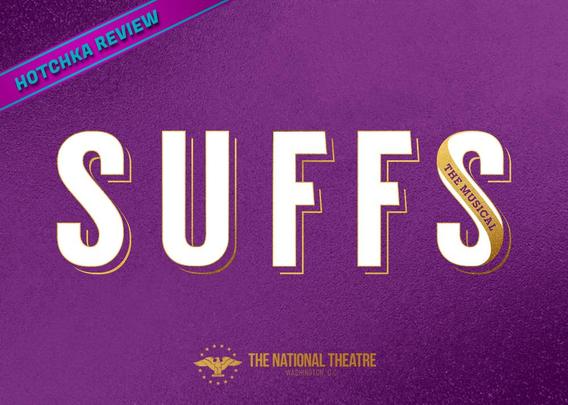 Hotchka Review: Suffs. Bold white text reading "SUFFS" with "THE MUSICAL" vertically in the "S" on a gold sash, on a textured purple background, conveying a theatrical theme. The National Theatre logo is in gold at the bottom center.